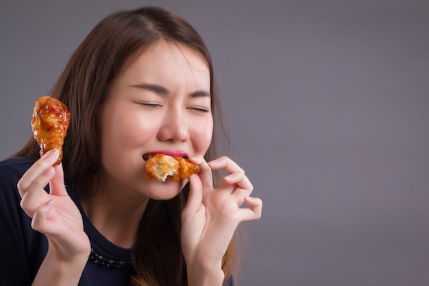 Hungry Asian woman eating fried chicken