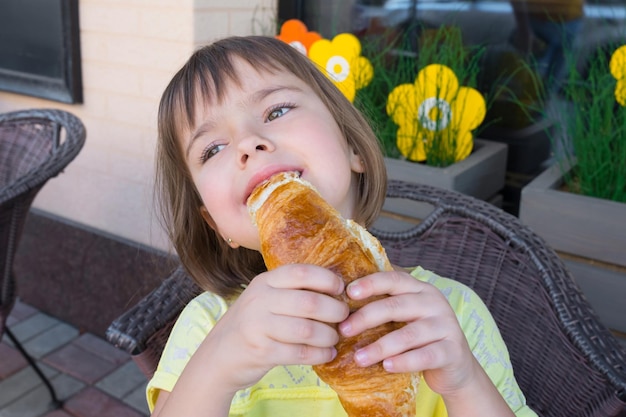 The hungry Child appetizingly eats fresh croissant