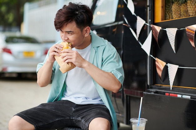 おいしいサンドイッチを食べる空腹の男