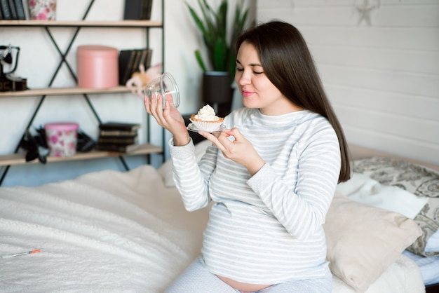 Donna incinta affamata che mangia alimento malsano - torte. voglie dolci durante il concetto di gravidanza.