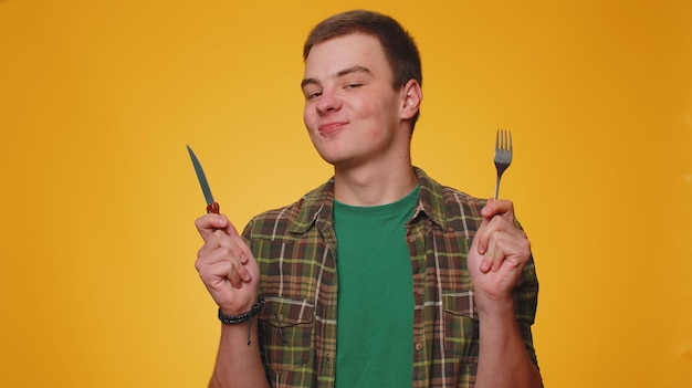 Hungry teenager adult boy waiting for serving dinner dishes with fork and knife delicious restaurant