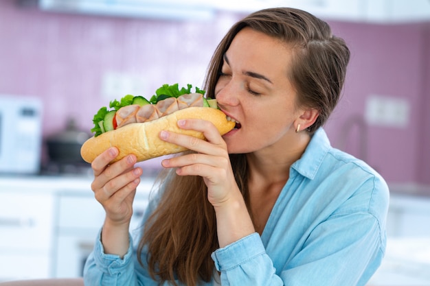 Hungry woman eat homemade sandwich. Gluttony and overweight because of harmful fast food and unhealthy eating