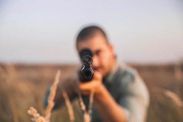 Foto il cacciatore mira sul campo con un fucile da cecchino. concentrarsi sulla museruola
