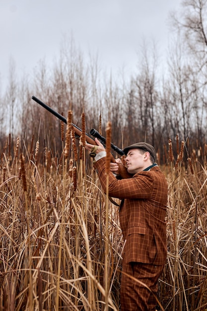 Photo hunter male. shooter sighting in target. hunting period. male with gun in field.