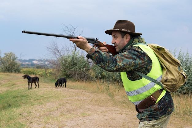 Uomo cacciatore in mimetica con una pistola durante la caccia alla ricerca di uccelli selvatici o selvaggina stagione di caccia autunnale