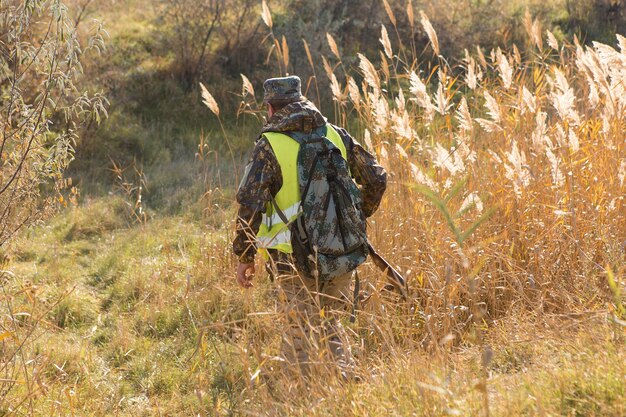 Foto uomo cacciatore mimetico con pistola durante la caccia alla ricerca di uccelli selvatici o selvaggina caccia autunnale