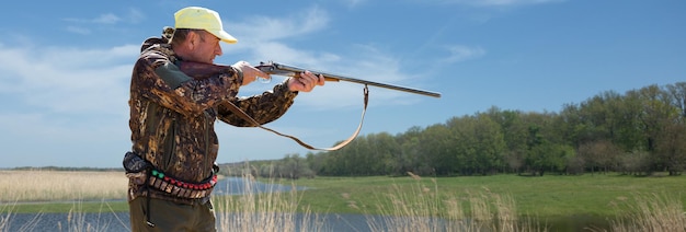 Photo hunter man in camouflage with a gun during the hunt in search of wild birds or game