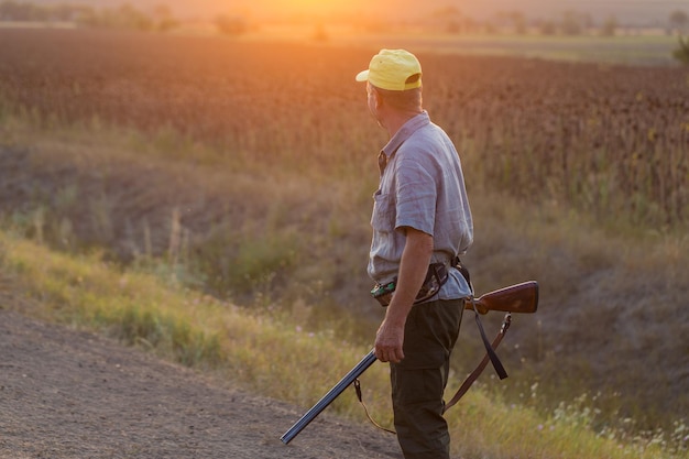 Foto uomo cacciatore in mimetica con una pistola durante la caccia alla ricerca di uccelli selvatici o selvaggina
