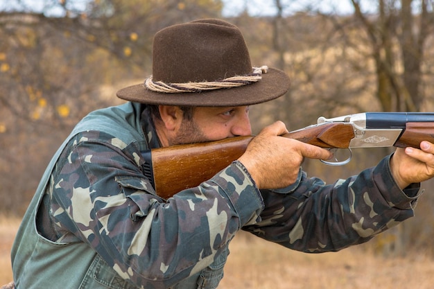 Foto uomo cacciatore in mimetica con una pistola durante la caccia alla ricerca di uccelli selvatici o selvaggina