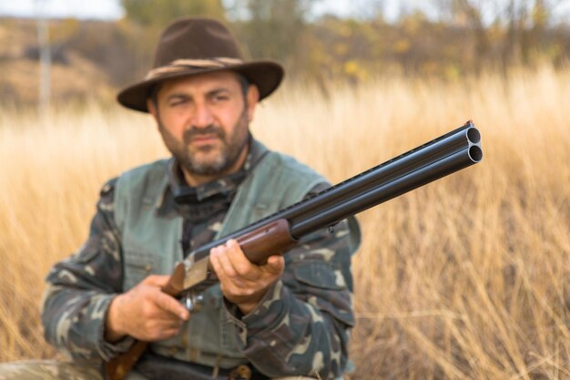 Hunter man in camouflage with a gun during the hunt in search of wild birds or game Autumn hunting season