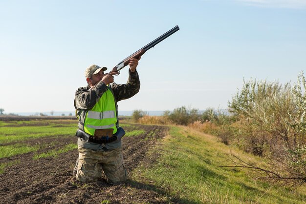 Hunter man in camouflage with a gun during the hunt in search of wild birds or game Autumn hunting season