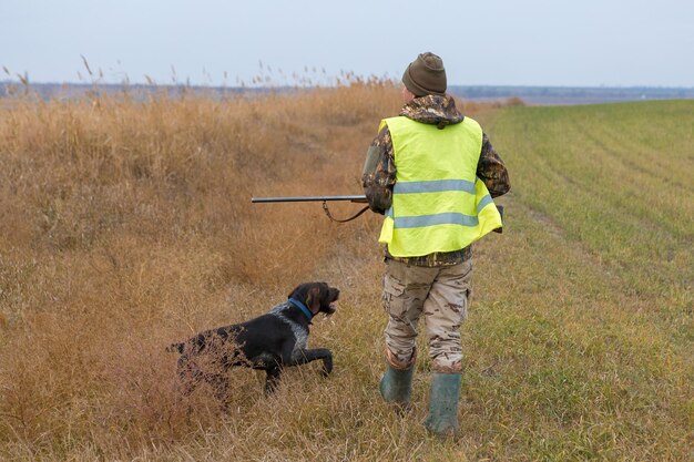 野鳥やゲームの秋の狩猟シーズンを探して狩り中に銃を持ったカモフラージュのハンター男