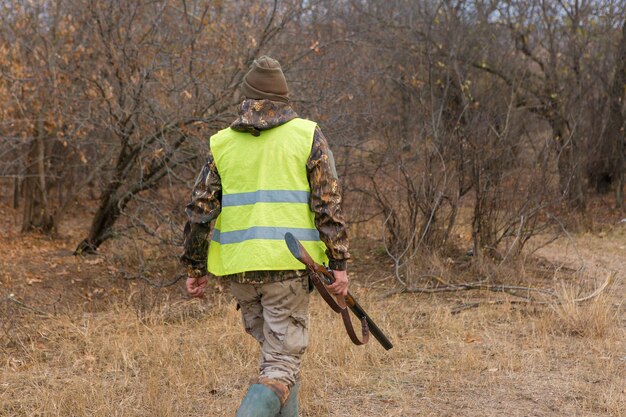 野鳥やゲームの秋の狩猟シーズンを探して狩り中に銃を持ったカモフラージュのハンター男