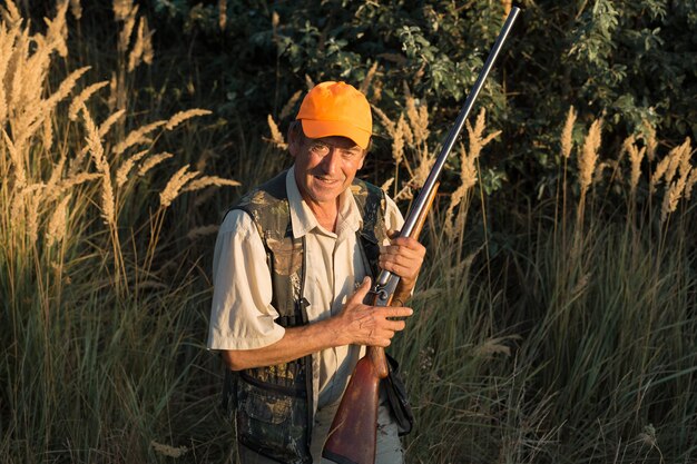 野鳥やゲームを探して狩りをしているときに銃を持ってカモフラージュしたハンターマン。秋の狩猟シーズン。