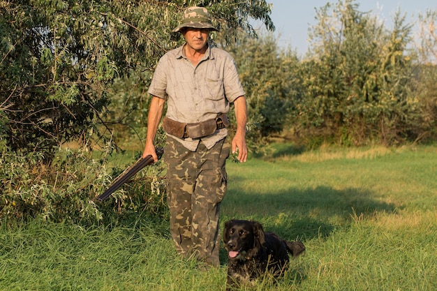 Hunter man in camouflage with a gun during the hunt in search of wild birds or game