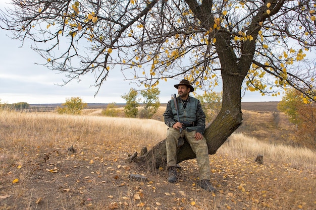 Человек-охотник в камуфляже с ружьем во время охоты в поисках диких птиц или дичи