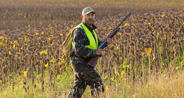 Hunter man in camouflage with a gun during the hunt in search of wild birds or game