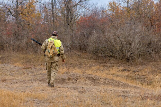 野鳥やゲームを探して狩り中に銃でカモフラージュのハンター男