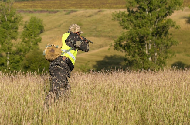 Hunter man in camouflage with a gun during the hunt in search of wild birds or game