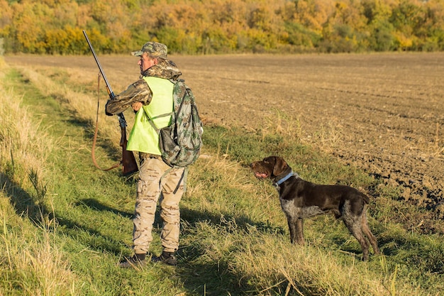 Hunter man in camouflage with a gun during the hunt in search of wild birds or game