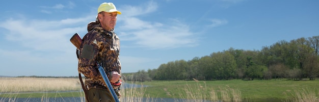 Hunter man in camouflage with a gun during the hunt in search of wild birds or game