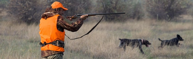 Hunter man in camouflage with a gun during the hunt in search of wild birds or game