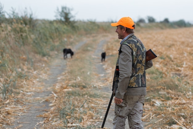 Hunter man in camouflage with a gun during the hunt in search of wild birds or game