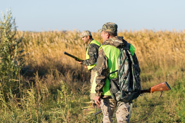 Hunter man in camouflage with a gun during the hunt in search of wild birds or game