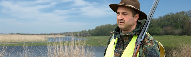 Hunter man in camouflage with a gun during the hunt in search of wild birds or game