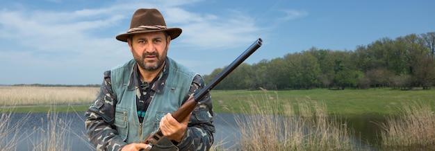 Hunter man in camouflage with a gun during the hunt in search of wild birds or game