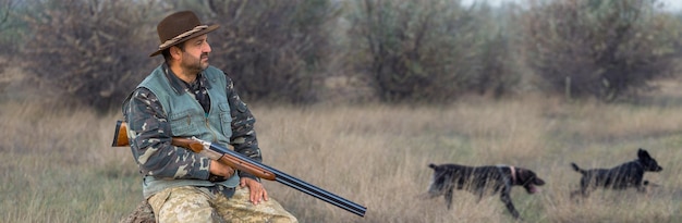 Hunter man in camouflage with a gun during the hunt in search of wild birds or game