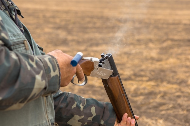 野鳥やゲームを探して狩り中に銃でカモフラージュのハンター男