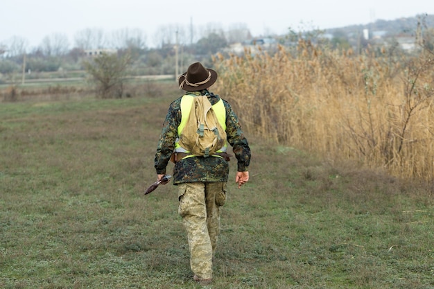 Hunter man in camouflage with a gun during the hunt in search of wild birds or game