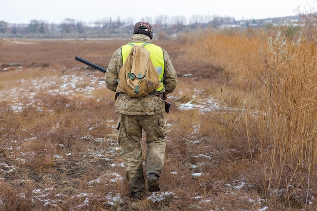 Hunter man in camouflage with a gun during the hunt in search of wild birds or game