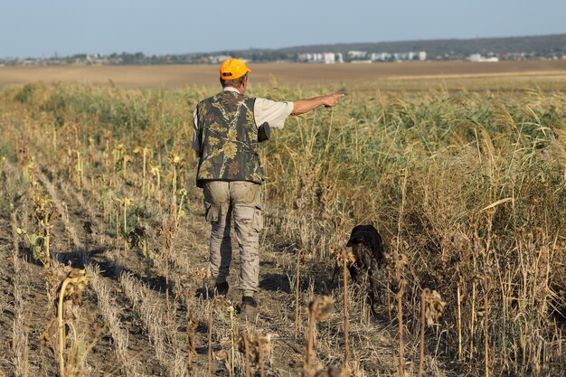 Hunter man in camouflage with a gun during the hunt in search of wild birds or game