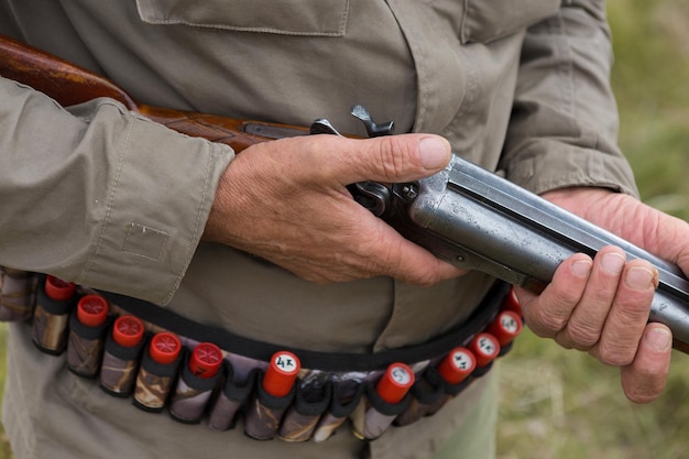 野鳥やゲームを探して狩りをしているときに銃を持ってカモフラージュをしているハンターの男。