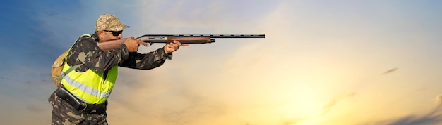 Hunter man in camouflage with a gun during the hunt in search of wild birds or game.