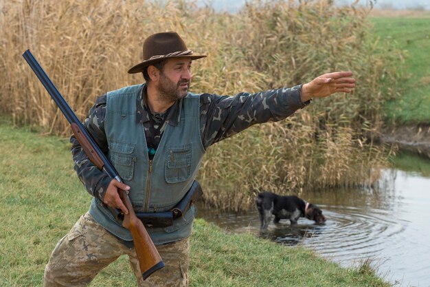 Hunter man in camouflage with a gun during the hunt in search of wild birds or game