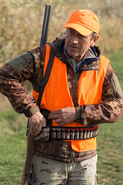 Hunter man in camouflage with a gun during the hunt in search of wild birds or game