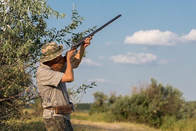 Hunter man in camouflage with a gun during the hunt in search of wild birds