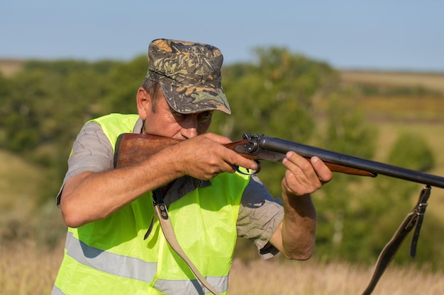 Hunter man in camouflage with a gun during the hunt in search of wild birds