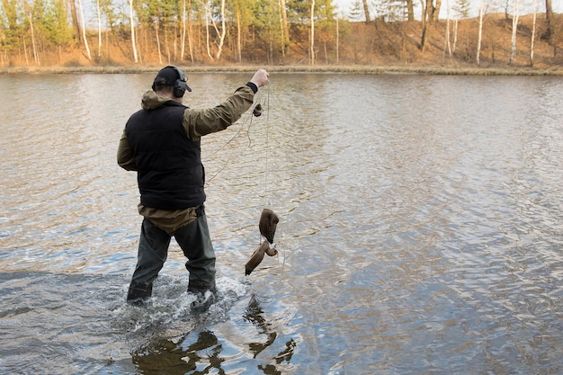 Foto l'uomo cacciatore caccia con una pistola per le anatre sulla riva del fiume