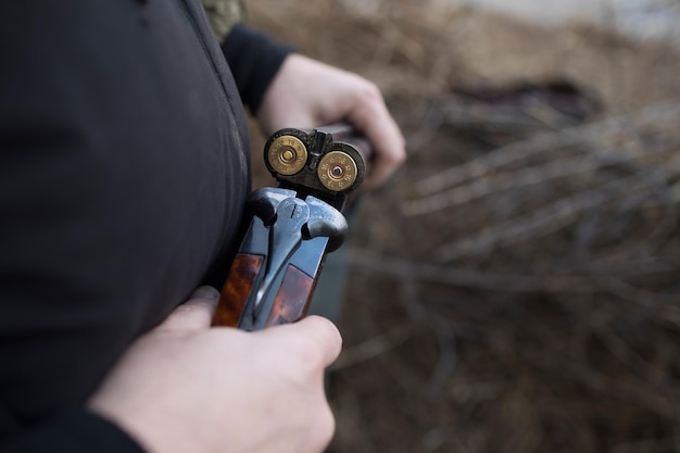 Hunter man hunts with a gun for ducks on the river bank