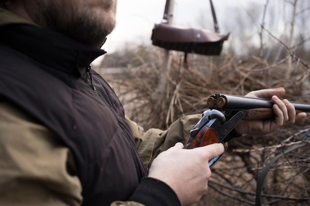 Hunter man hunts with a gun for ducks on the river bank