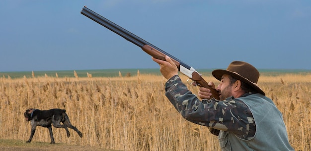 Фото Охотник в камуфляже с ружьем во время охоты в поисках диких птиц или дичи. осенний сезон охоты.