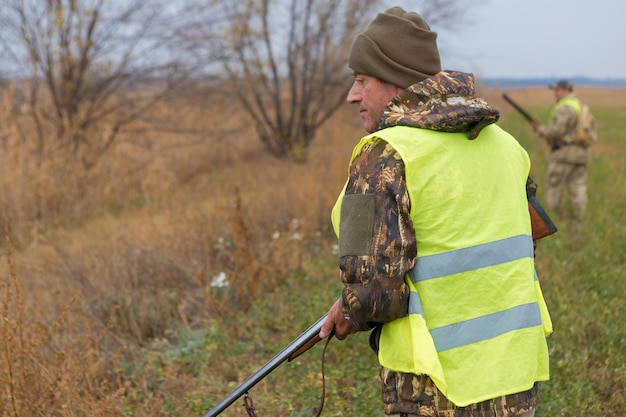 Фото Человек-охотник в камуфляже с ружьем во время охоты в поисках диких птиц или дичи.