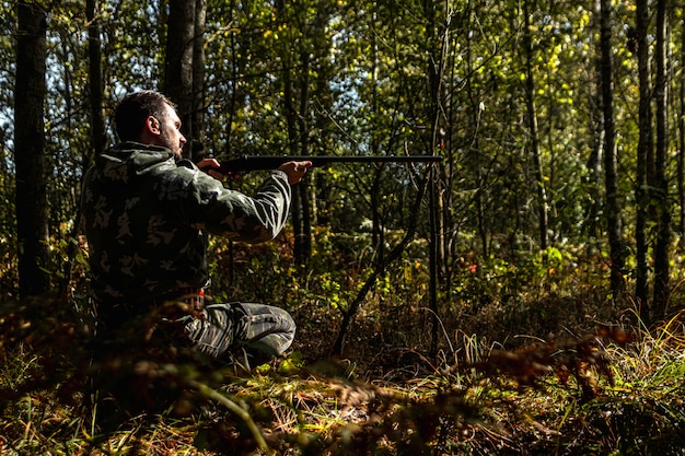 写真 野鳥を探して狩り中に銃でカモフラージュのハンター男