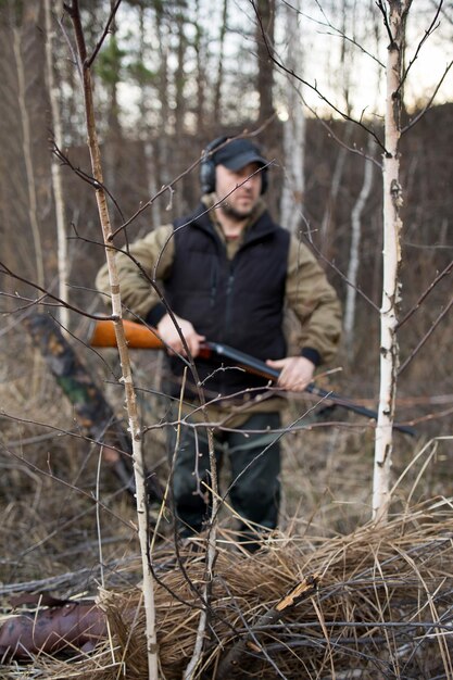 Hunter man jaagt met een geweer op eenden aan de oever van de rivier