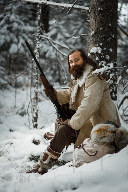 Hunter man in winter warm vintage clothes with gun in winter forest