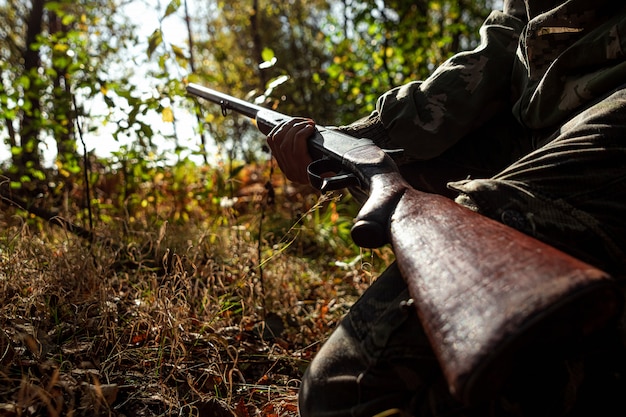 写真 秋の森でハンティング服を着た手に銃を持つハンター